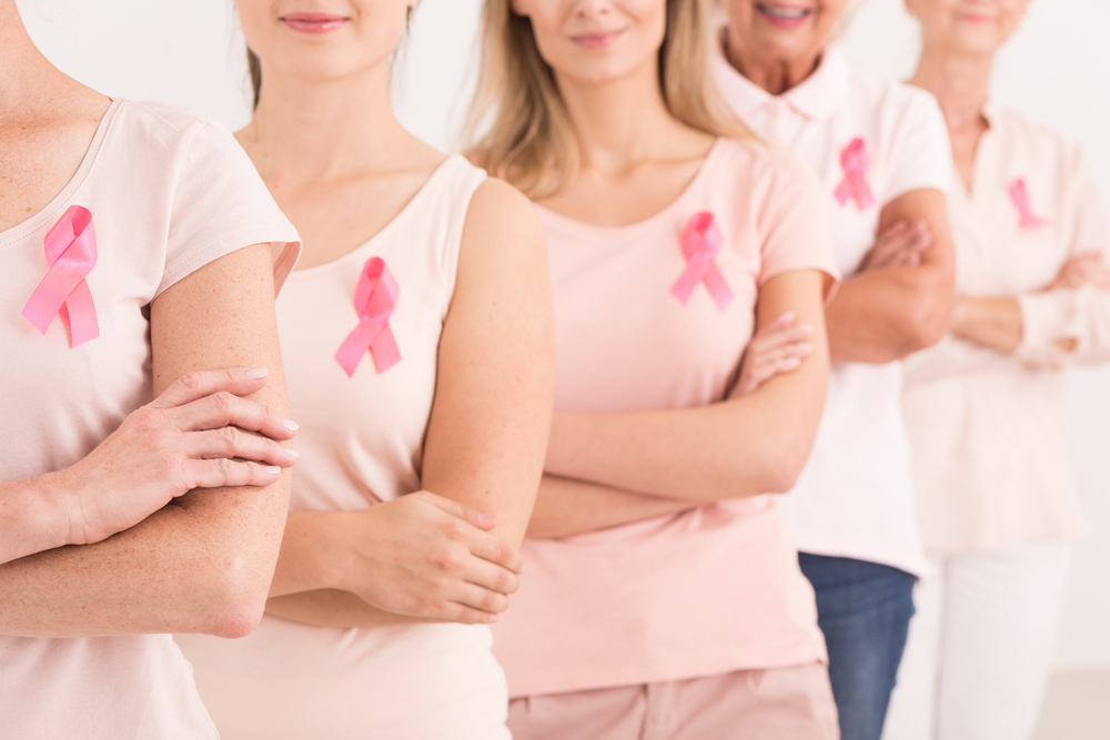 women together with pink shirts and pink ribbons for breast cancer awareness
