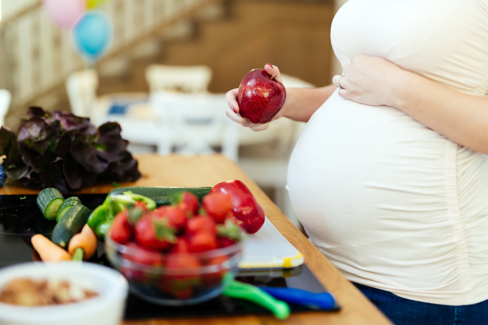 pregnant woman with fruit and vegetables on counter