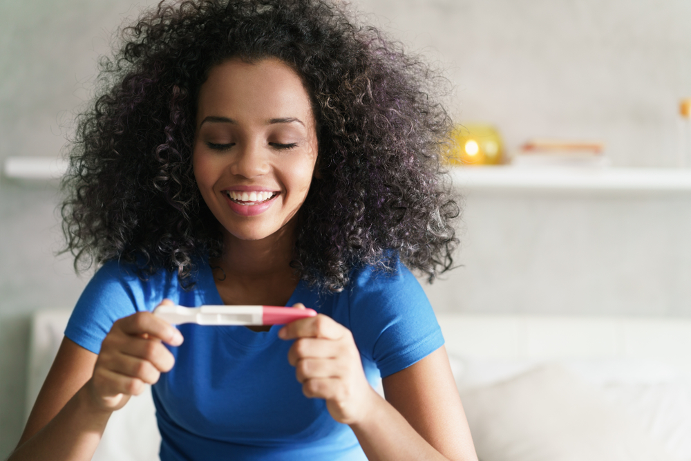 happy woman looking at pregnancy test results