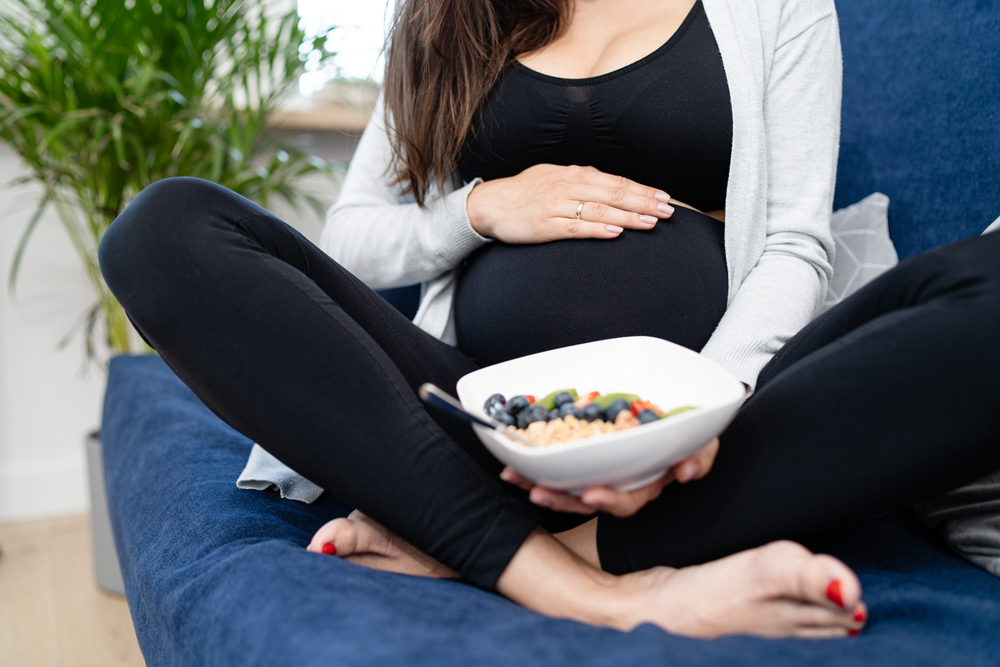 pregnant woman eating healthy food in bowl