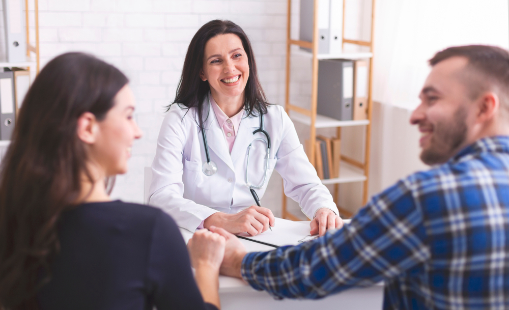 man and woman smiling at one another, talking to doctor