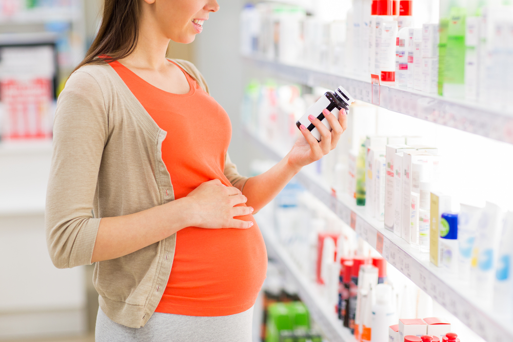 Pregnant woman looking at medicine