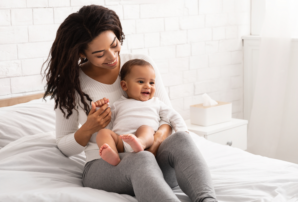 Woman holding baby while sitting on bed