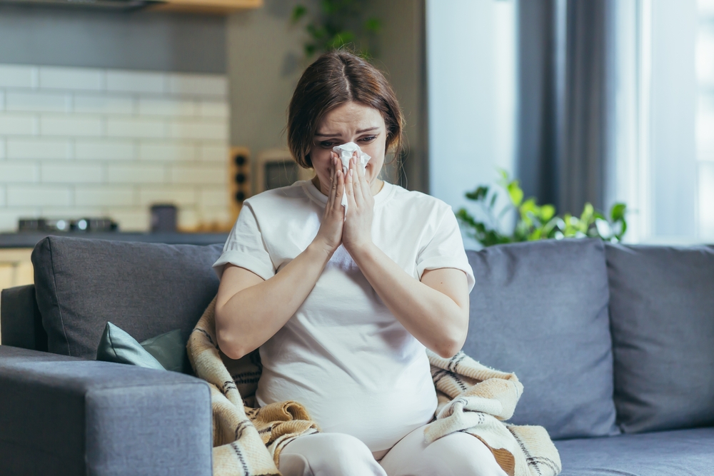 Pregnant woman blowing her nose.